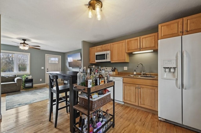 kitchen with a ceiling fan, a sink, white appliances, light wood-style floors, and baseboards