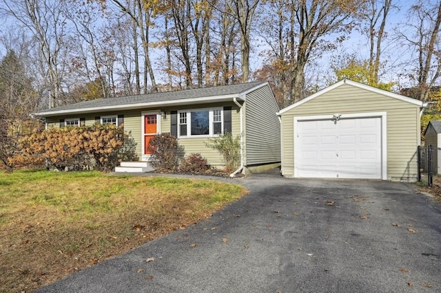 ranch-style home featuring a front lawn, an outbuilding, and driveway