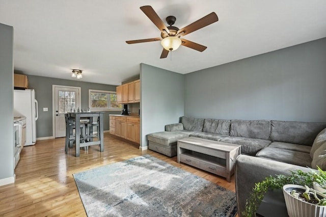 living area featuring light wood-type flooring, baseboards, and ceiling fan