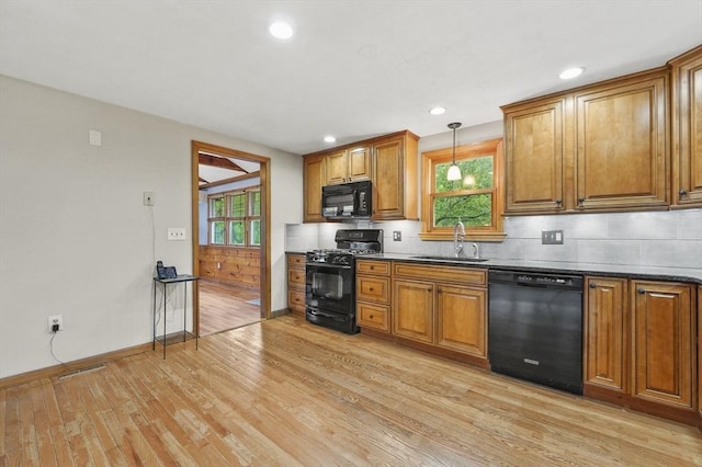 kitchen with black appliances, a sink, light wood finished floors, brown cabinets, and recessed lighting
