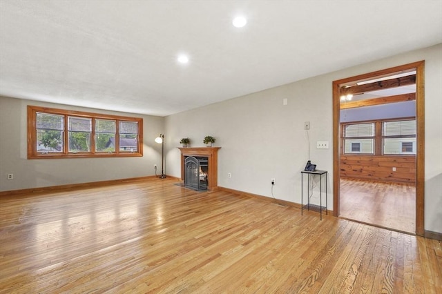 unfurnished living room with light wood-style floors, baseboards, recessed lighting, and a fireplace with flush hearth