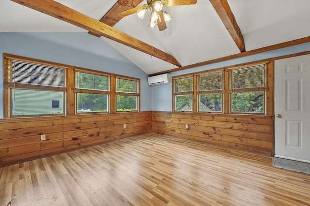 empty room with a wall mounted air conditioner, light wood-type flooring, wooden walls, ceiling fan, and a wainscoted wall