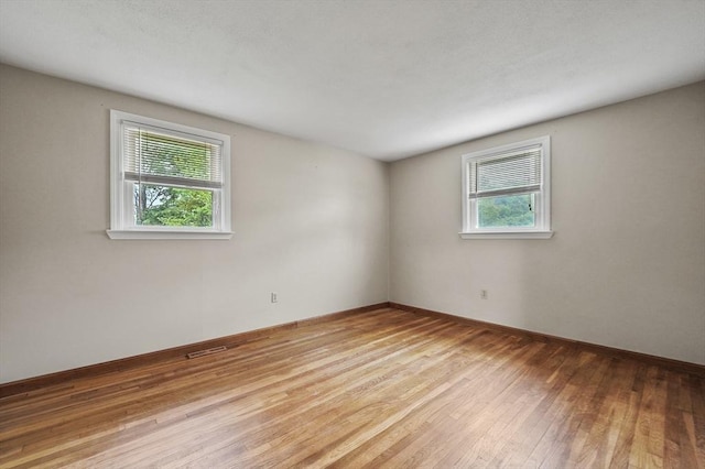 spare room with wood-type flooring and baseboards