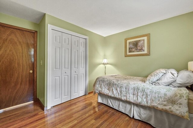 bedroom with a closet, wood finished floors, and baseboards