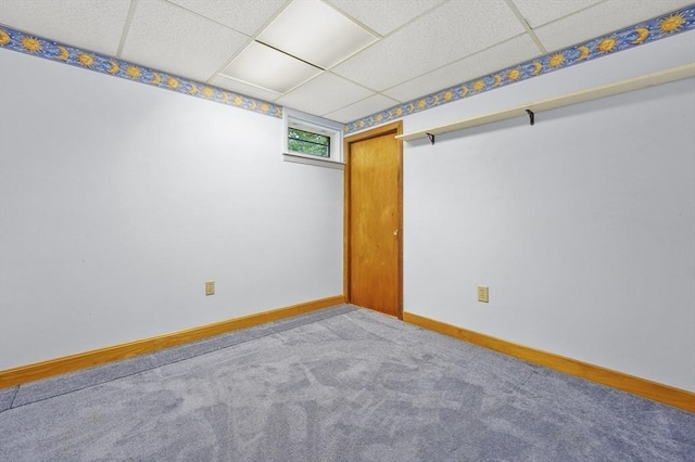 spare room with a paneled ceiling, baseboards, and carpet