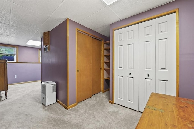 corridor featuring carpet flooring, a paneled ceiling, and baseboards