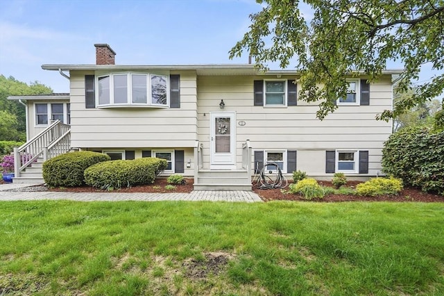 bi-level home featuring a chimney and a front yard