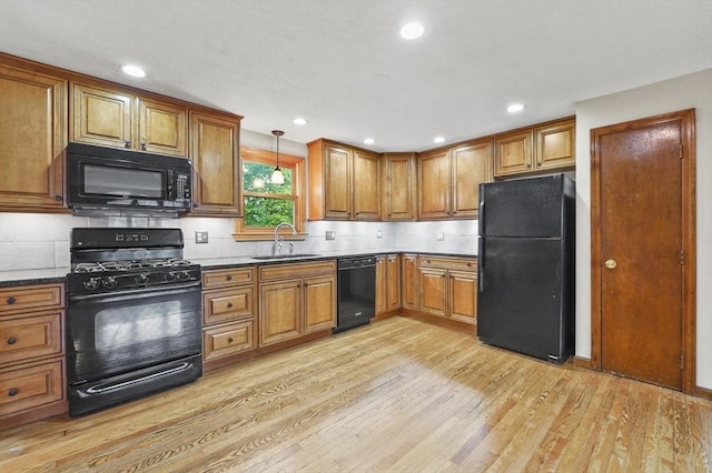 kitchen featuring black appliances, a sink, brown cabinets, light wood-style floors, and backsplash