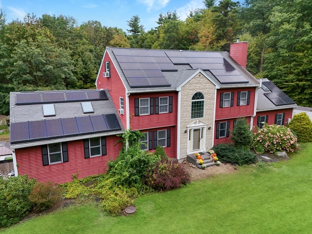 rear view of property with a yard and solar panels