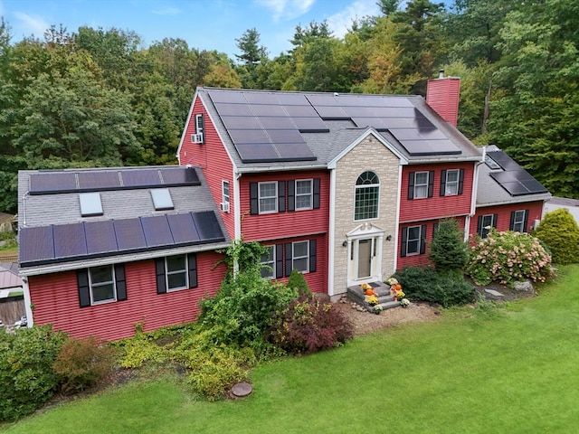 rear view of property with a yard and solar panels