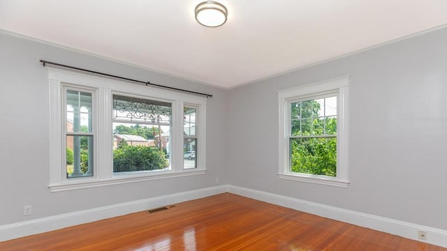 empty room with visible vents, baseboards, and wood finished floors