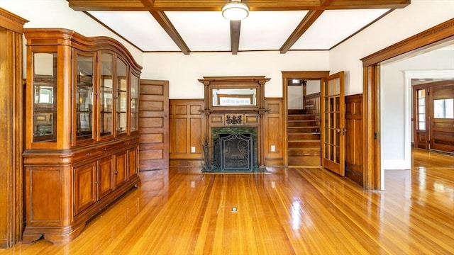 unfurnished living room featuring light wood finished floors, beam ceiling, stairs, and a fireplace with flush hearth