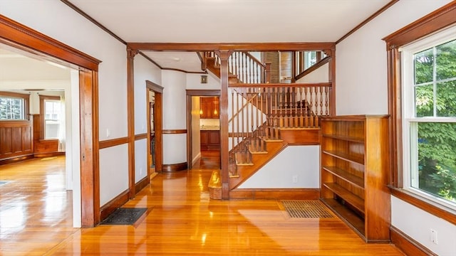 staircase featuring crown molding, wood finished floors, and baseboards