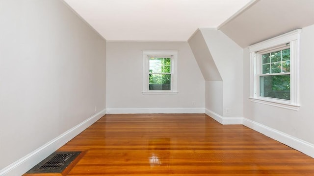 additional living space featuring lofted ceiling, wood finished floors, visible vents, and baseboards