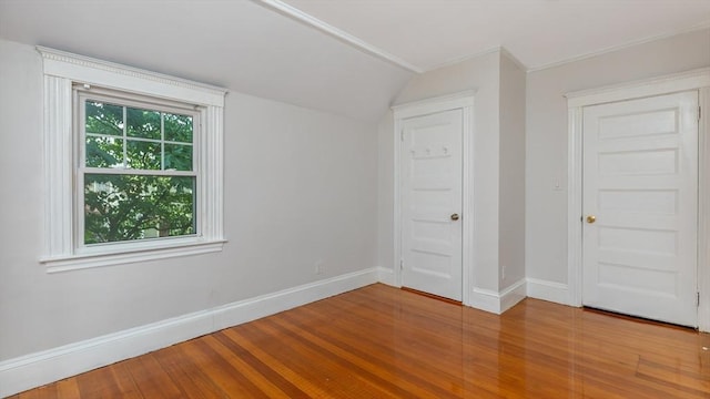 unfurnished room featuring baseboards, lofted ceiling, and wood finished floors