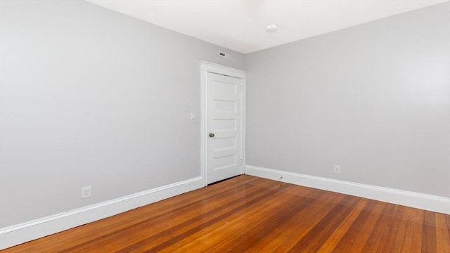 empty room with visible vents, wood finished floors, and baseboards