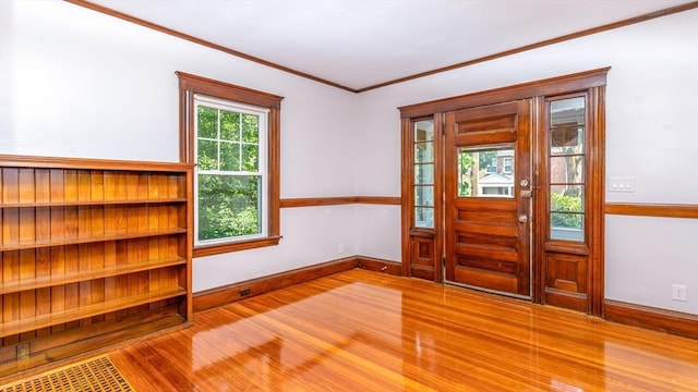 foyer with wood finished floors, baseboards, and ornamental molding