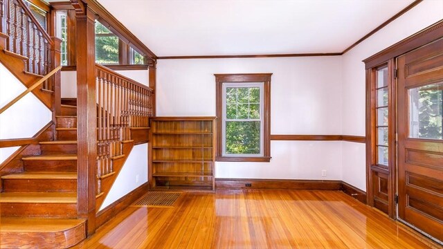 foyer with stairs, crown molding, wood finished floors, and baseboards