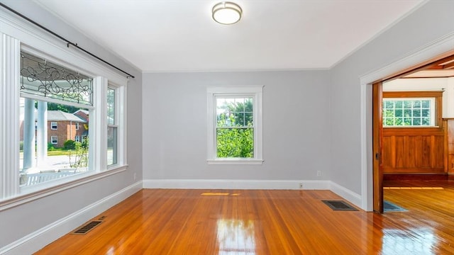 unfurnished room with wood finished floors, visible vents, and baseboards