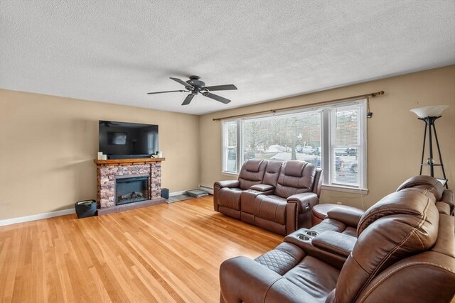 living area with baseboard heating, a fireplace, baseboards, and wood finished floors