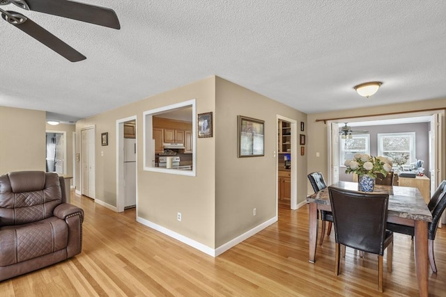 dining room featuring light wood-style flooring, baseboards, and ceiling fan