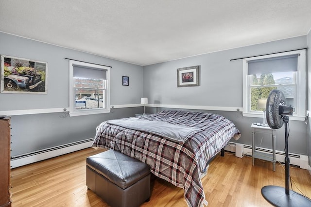 bedroom featuring a baseboard heating unit and wood finished floors