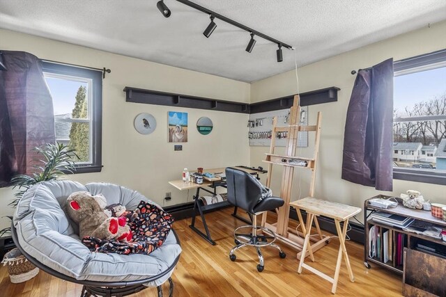 office space with rail lighting, a textured ceiling, and wood finished floors