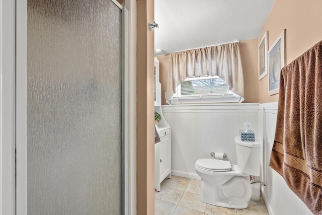 full bath with tile patterned floors, wainscoting, toilet, and a shower stall