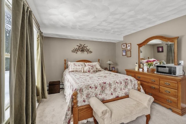 bedroom with a baseboard heating unit and light colored carpet