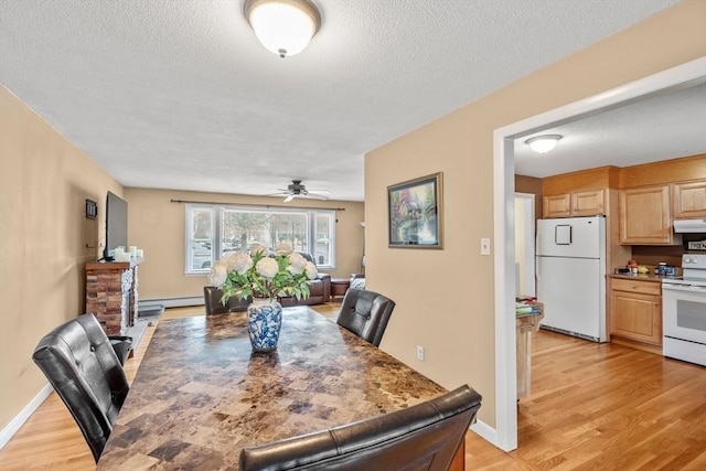 dining space with light wood finished floors, baseboards, baseboard heating, a textured ceiling, and a ceiling fan