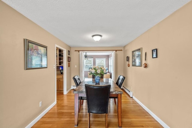 dining room featuring baseboard heating, light wood-type flooring, baseboards, and a baseboard radiator