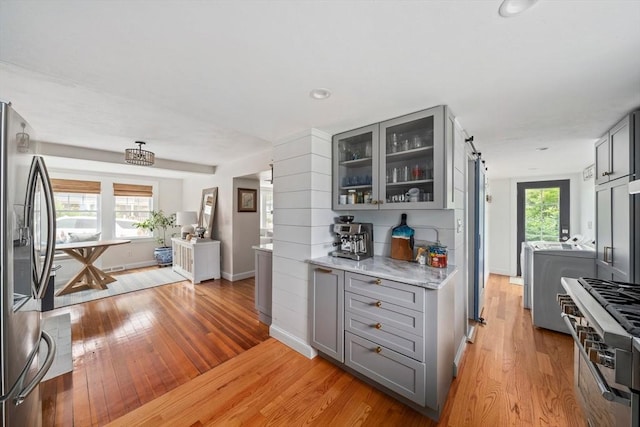 16 Squanto Rd, Weymouth, MA 02191 - kitchen featuring gray cabinets, appliances with stainless steel finishes, light wood-style floors, glass insert cabinets, and washing machine and dryer