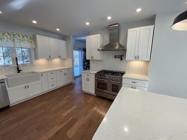 kitchen with white cabinets, appliances with stainless steel finishes, sink, and wall chimney exhaust hood