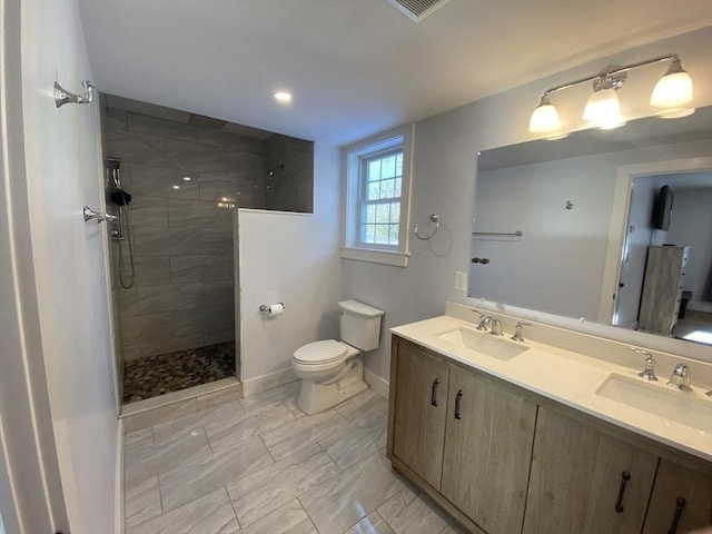 bathroom featuring toilet, vanity, and tiled shower