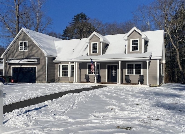 cape cod home featuring covered porch and a garage