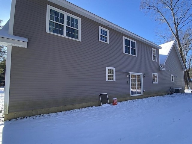 snow covered house featuring central air condition unit