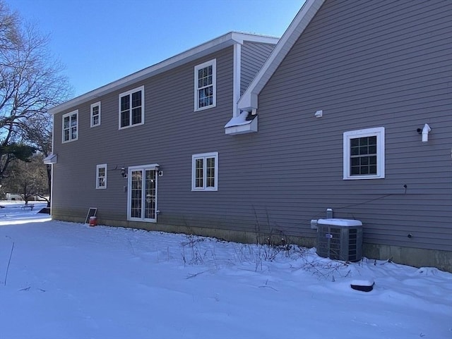 snow covered house featuring central AC