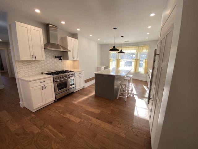 kitchen featuring double oven range, wall chimney range hood, white cabinets, and a center island