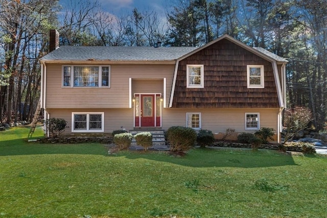 bi-level home featuring a chimney and a front lawn