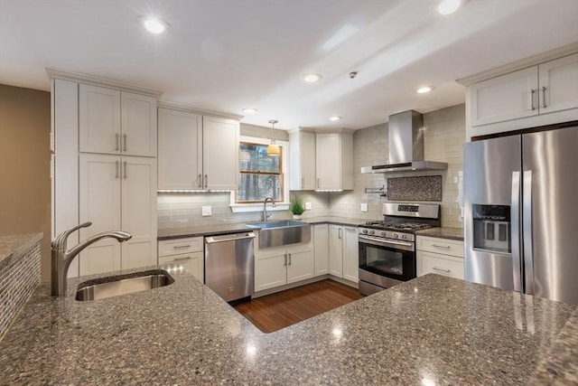 kitchen featuring a sink, wall chimney range hood, backsplash, and stainless steel appliances