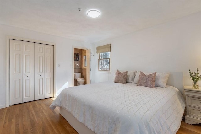 bedroom with connected bathroom, a closet, and wood finished floors