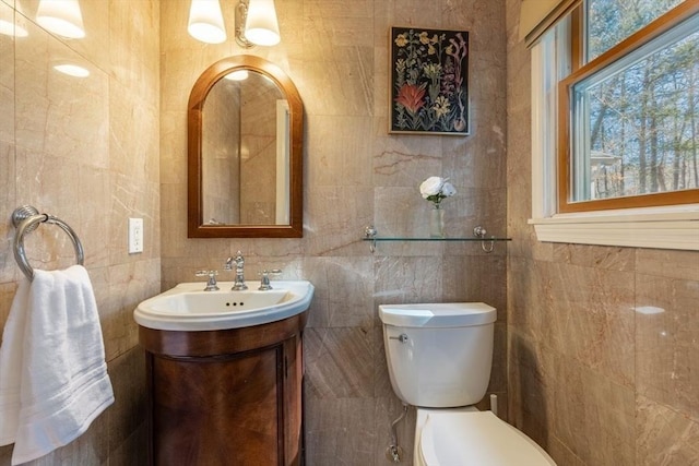 half bathroom with vanity, tile walls, and toilet