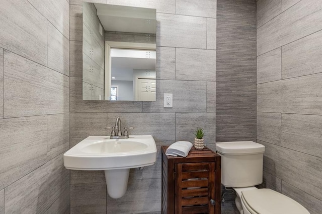 bathroom featuring toilet and tile walls