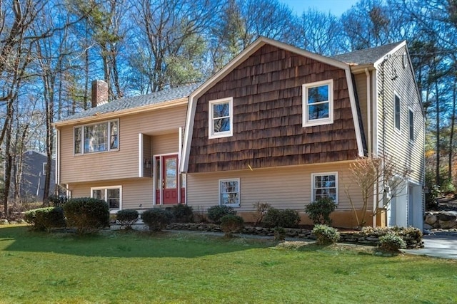 raised ranch with an attached garage, a chimney, and a front lawn