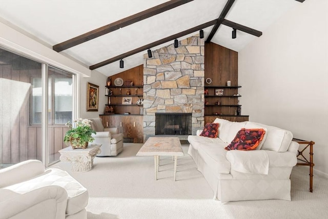 living room with a stone fireplace, carpet, and vaulted ceiling with beams