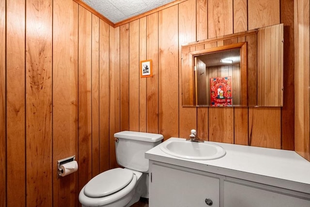 bathroom featuring vanity, a textured ceiling, toilet, and wood walls