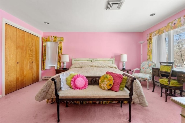 carpeted bedroom featuring baseboard heating and a closet