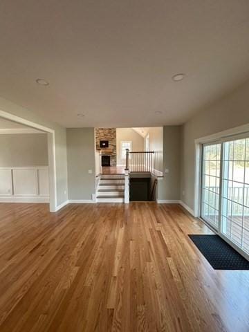 unfurnished living room featuring a decorative wall, wood finished floors, and baseboards