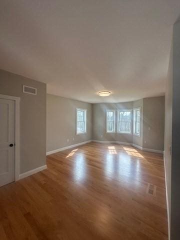 spare room with visible vents, wood finished floors, and baseboards