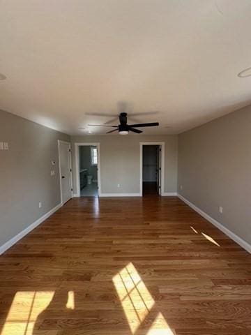 unfurnished living room featuring ceiling fan, baseboards, and wood finished floors